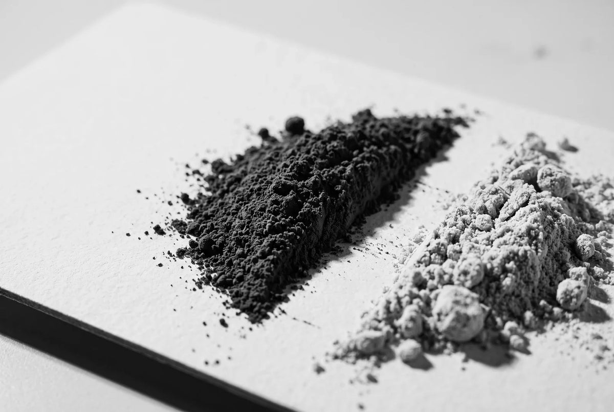 Deux tas de poudre de textures différentes posés côte à côte sur du carton mat blanc, séparés par une bande de carton nu