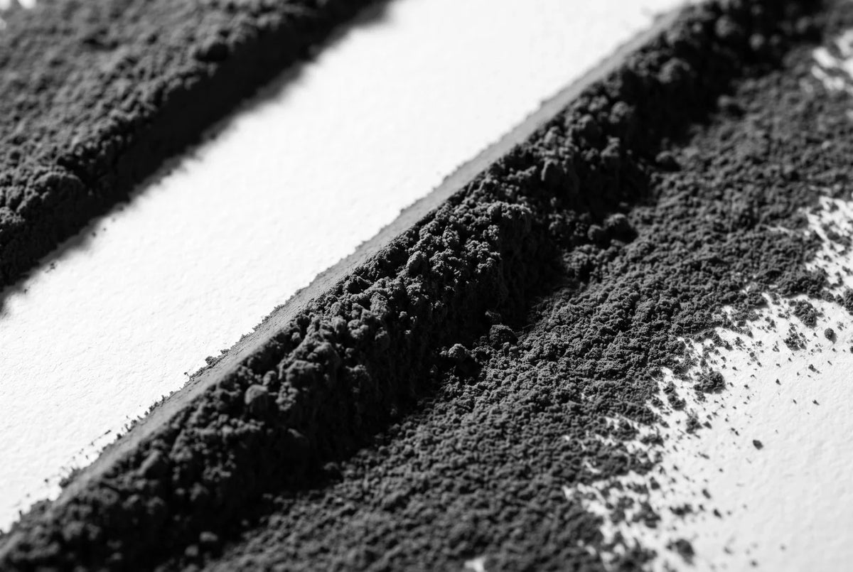 Nappe mince de poudre de cacao raclée sur du papier mat blanc, avec une bande de papier laissée nue et une crête vive sur le bord