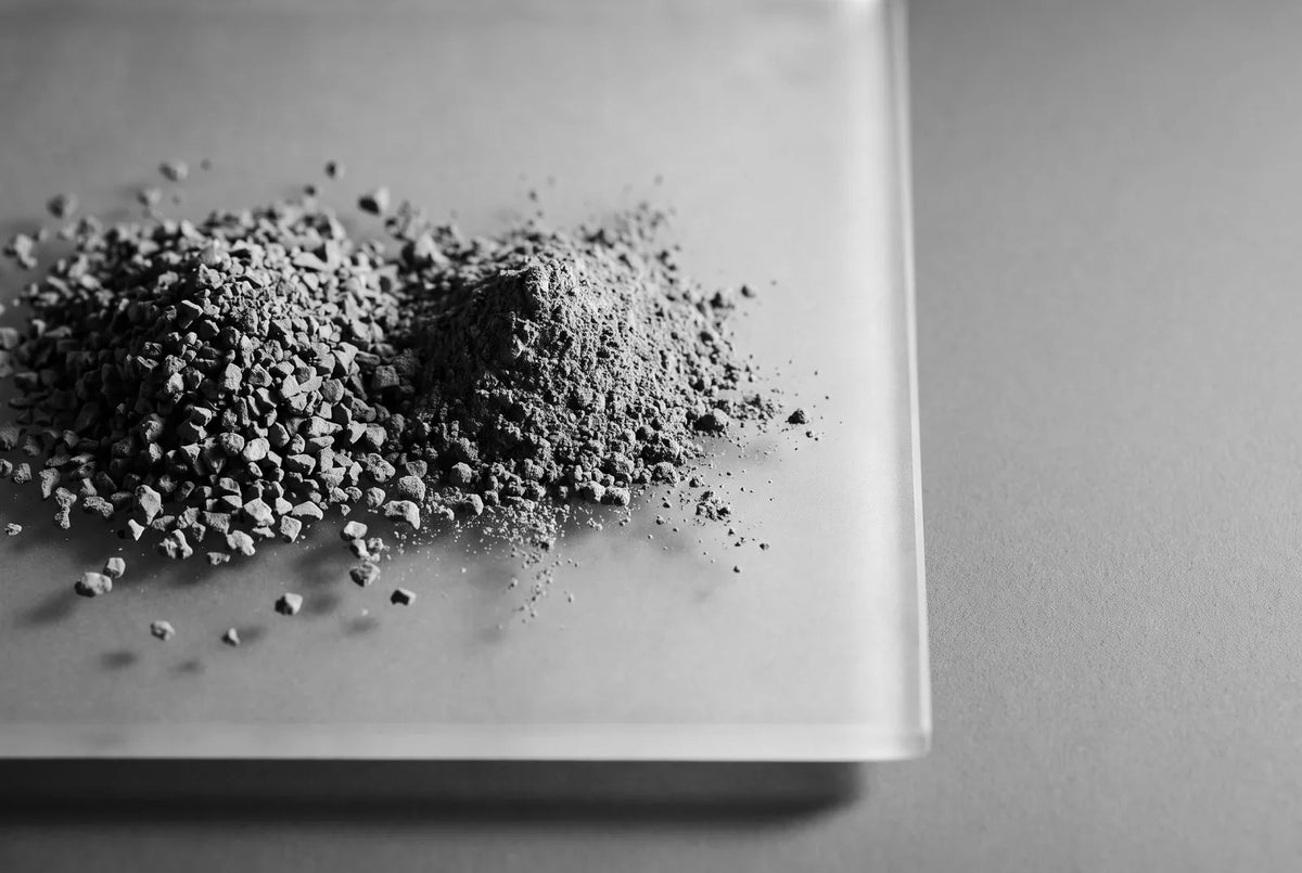 Granulés de café instantané et poudre de cacao en deux tas bas sur une plaque de verre dépoli, vus de très près en lumière rasante